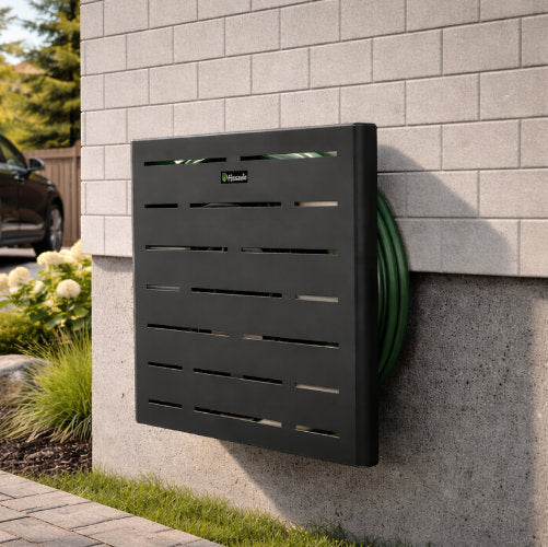 Wall-mounted black hose reel with green hose on a gray brick wall