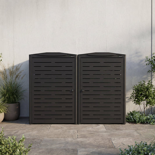 Two black outdoor storage units against a light gray wall with plants around.