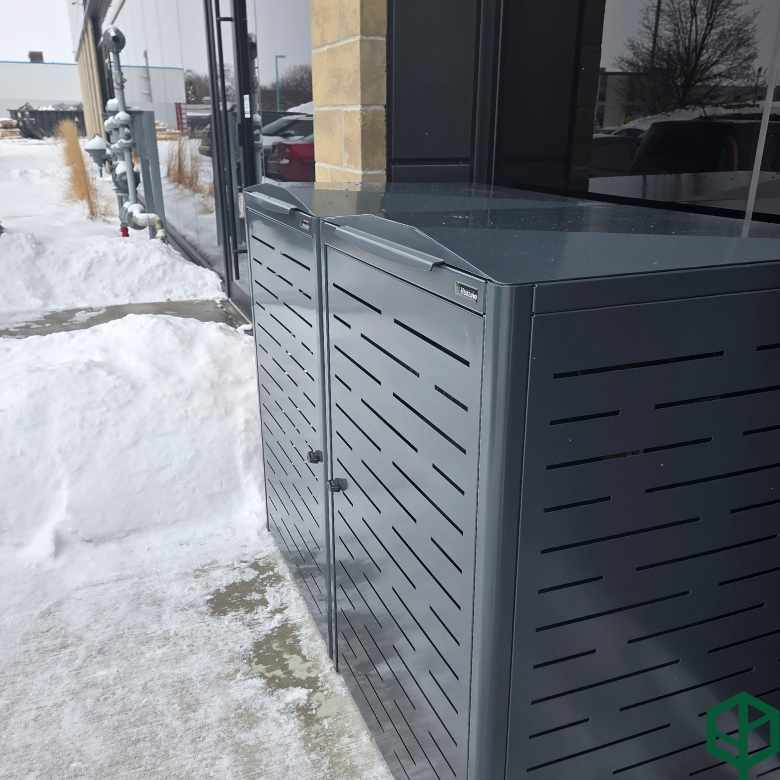 Outdoor trash bin against a building with snow on the ground