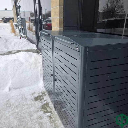 Outdoor trash bin against a building with snow on the ground
